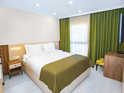 a bedroom with a large bed with green curtains at Quinnova Hotel in Istanbul