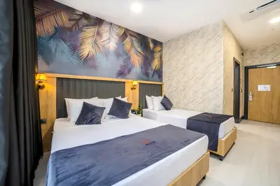 two beds in a room with a mural on the wall at Bulton Hotel Airport in Arnavutköy