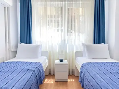 two beds in a room with blue curtains and a window at Near Nişantasi & Stylish No1 in Istanbul