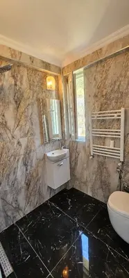 a bathroom with a sink and a toilet and a mirror at Luxury villa with sea and forest view in Döngel