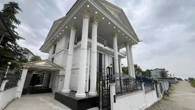 a large white building with columns and a fence at Luxury Skylights Villa in Kullar