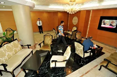 a man walking through a lobby with two men sitting at tables at Ilıcak Hotel in Istanbul