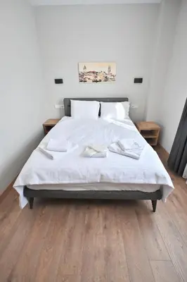 a bedroom with a bed with white sheets and wooden floors at The Han YK Hotel in Avcılar