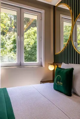 a bedroom with a bed with a green pillow and a mirror at Sistina Old City Hotel in Istanbul