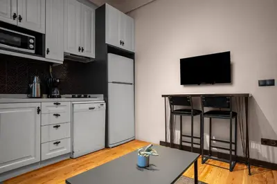 a kitchen with white cabinets and a tv on the wall at Charming 1BR Flat with Balcony in Cihangir in Istanbul