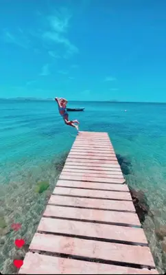 a person jumping off a dock into the water at ADASU Otel in Marmara