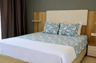 a bedroom with a large white bed with blue pillows at ADASU Otel in Marmara