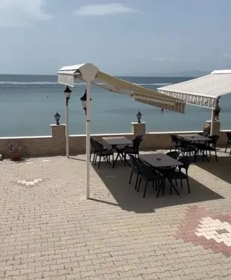 a patio with tables and umbrellas on the beach at Kum Motel in Marmara