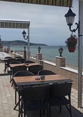 a row of tables and chairs with the ocean in the background at Kum Motel in Marmara