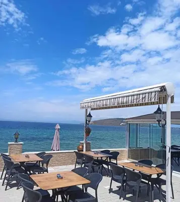 a group of tables and chairs next to the ocean at Kum Motel in Marmara