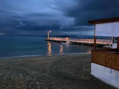 a pier on a beach with a cloudy sky at Kalemi Pansiyon in Marmara
