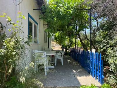 a table and chairs next to a building with a blue fence at Kalemi Pansiyon in Marmara
