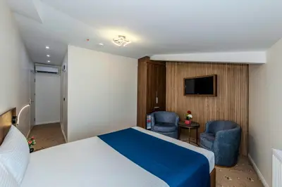 a hotel room with a bed and two chairs and a television at Airport Waves Hotel in Arnavutköy