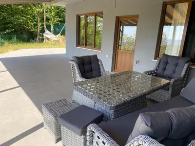 a patio with a glass table and wicker chairs at Kocaeli Başiskele Doğayla İç İçe Özel Havuzlu Tatil Evi in Bahçecik
