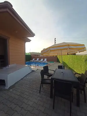 a patio with tables and chairs and an umbrella at Kandıra villam in Duraklı