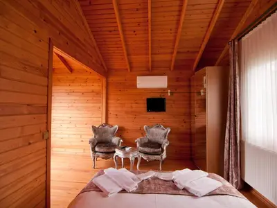 a bedroom with two chairs and a bed and a television at Gizemli Nehir Bungalov Otel in Agva