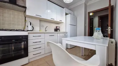 a kitchen with white cabinets and a white table and chairs at Sabina gokcene 5 dk in Istanbul