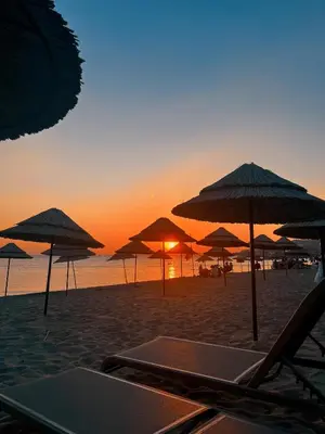 a group of umbrellas on a beach with the sunset at Yağcı Hotel Erdek in Erdek