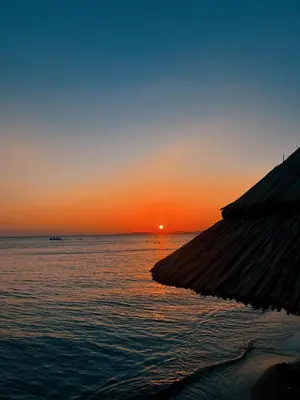a sunset over the ocean with a hut in the foreground at Yağcı Hotel Erdek in Erdek