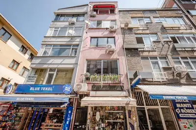 a tall pink building with shops in front of it at Kadıköy ün Kalbinde Tarihi Rahat Sessiz Daire in Istanbul