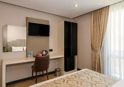 a bedroom with a bed and a desk with a chair at Hilltown Airport Hotel & Restaurant in Taşoluk
