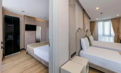 a hotel room with two beds and a tv at Hilltown Airport Hotel & Restaurant in Taşoluk