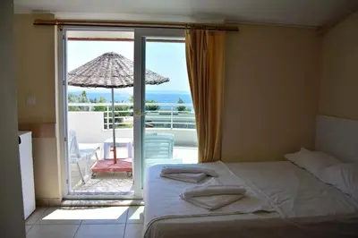 a bedroom with a bed and a balcony with an umbrella at Sare Hotel in Erdek