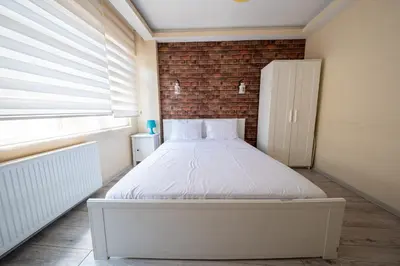 a white bed in a room with a brick wall at White Rose Apartments in Istanbul