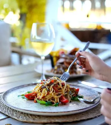 a person eating a plate of pasta with a glass of wine at Goga Otel in Sarıyer