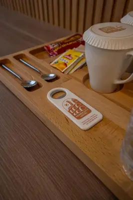 a wooden table with a cup of coffee and a spoon at Kemer City Hotel İstanbul Airport in Kemerburgaz