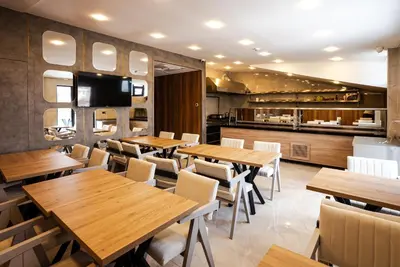 a restaurant with wooden tables and chairs and a kitchen at Kemer City Hotel İstanbul Airport in Kemerburgaz