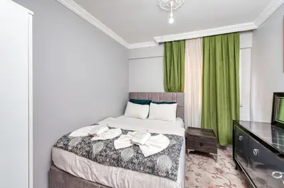 a bedroom with a bed with green curtains and a television at MARMARA DREAM APARt in Istanbul