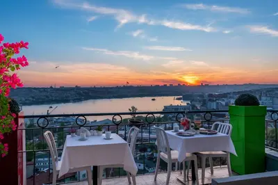 two tables and chairs on a balcony with a sunset at Big Urban Taksim Terrace Stay in Istanbul