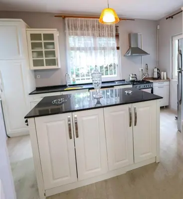 a kitchen with white cabinets and a black counter top at Villa Denizci in Sapanca