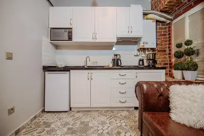 a kitchen with white cabinets and a couch in a room at Taksim Nil Suite in Istanbul