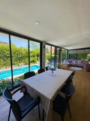 a dining room with a table and chairs and a pool at Cadde Sapanca Sıcak Havuzlu Geniş Bahçeli in Sapanca