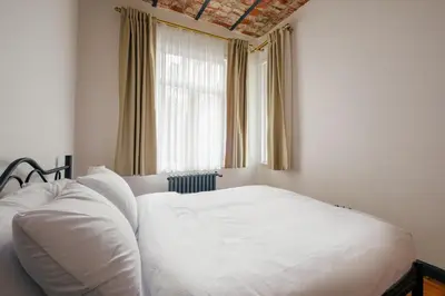 a white bed in a bedroom with a window at Cozy Flat with Balcony Near Istiklal Avenue in Istanbul