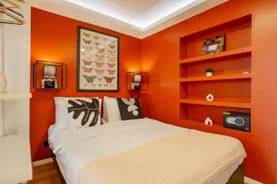 a bedroom with an orange wall with a bed and shelves at Cosy Apartment in Beyoglu in Istanbul