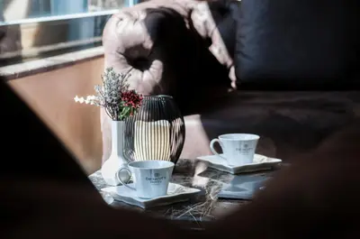 two coffee cups and a vase with flowers on a table at Dencity Hotels & Spa in Istanbul