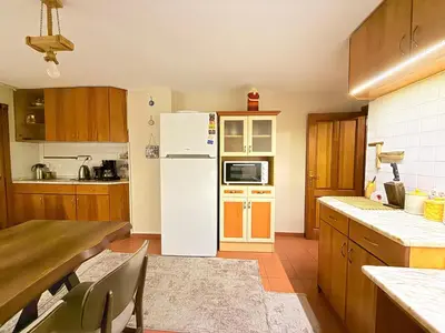 a kitchen with a white refrigerator and wooden cabinets at Manzara Ödüllü Büyük Havuzlu Premium Villa in Dibektaş