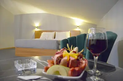 a table with a plate of fruit and a glass of wine at Rosse Hotel in Kırac