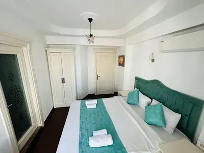 a bedroom with a green and white bed with blue pillows at LA MAİSON FAMILY Hotel in Istanbul