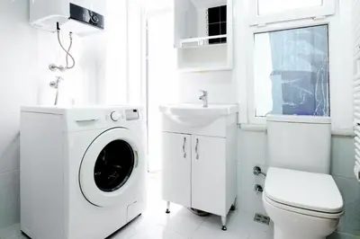 a white bathroom with a washing machine and a sink at Chic Apartment Walk to Maçka Park Nişantaşı in Istanbul