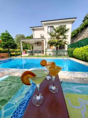 two martini glasses on a table next to a swimming pool at family villas sapanca in Sapanca