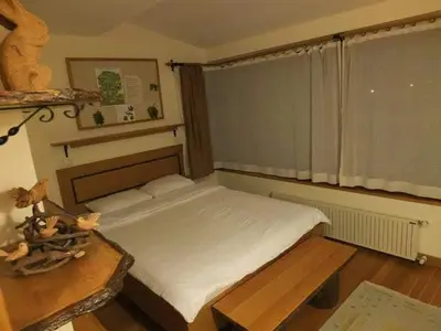 a bedroom with a bed and a table and a window at Meşeliev Pansiyon in Demirköy