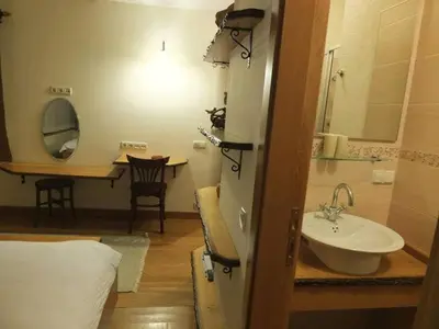 a bathroom with a sink and a mirror and a table at Meşeliev Pansiyon in Demirköy