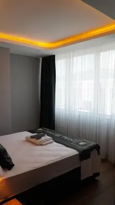 a bed in a room with a window with white curtains at Dual Hotel Halkalı in Istanbul