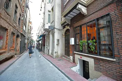 a woman walking a dog down a street at Wooden Style AC Galata in Istanbul