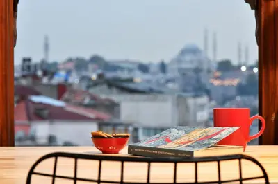 a book and a cup of coffee on a table with a window at Historical Flat Unique Terrace AC in Beyoğlu Galata in Istanbul