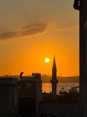 a sunset over the water with a clock tower at The Kinyas House - Apartment in Kadıköy Historical Fishermen's Market in Istanbul